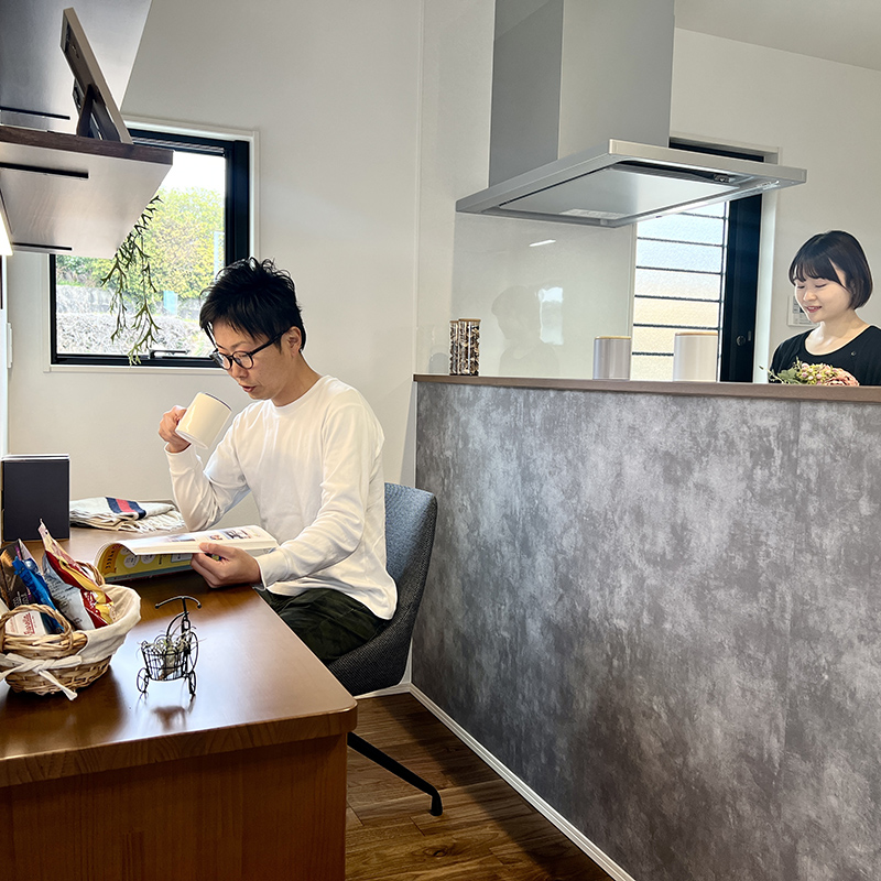 キッチン前のカウンターで読書をするご主人とキッチンで家事をする奥様 キッチン前のカウンターで読書をするご主人とキッチンで家事をする奥様